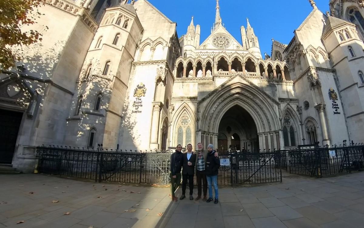 Uczestnicy wydarzenia pozują do grupowego zdjęcia stoją na zewnątrz budynku będącego siedzibą Royal Courts of Justice w Londynie.