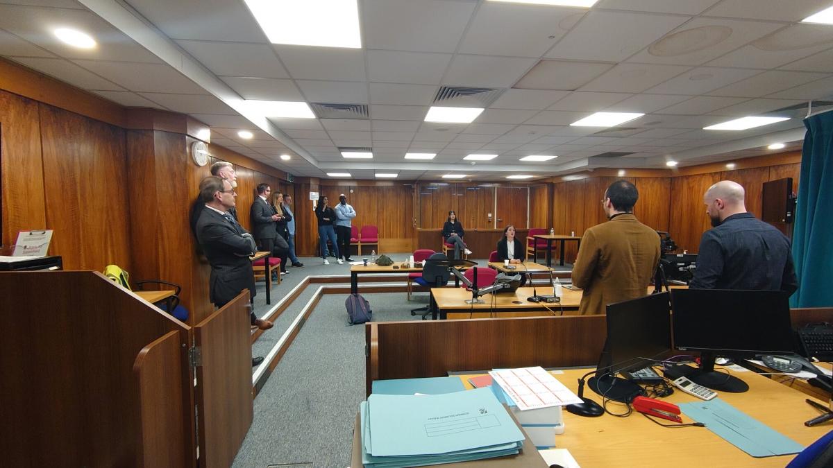Sala sądowa podczas nagrań. Uczestnicy stoją na sali sądowej podczas nagrania. 